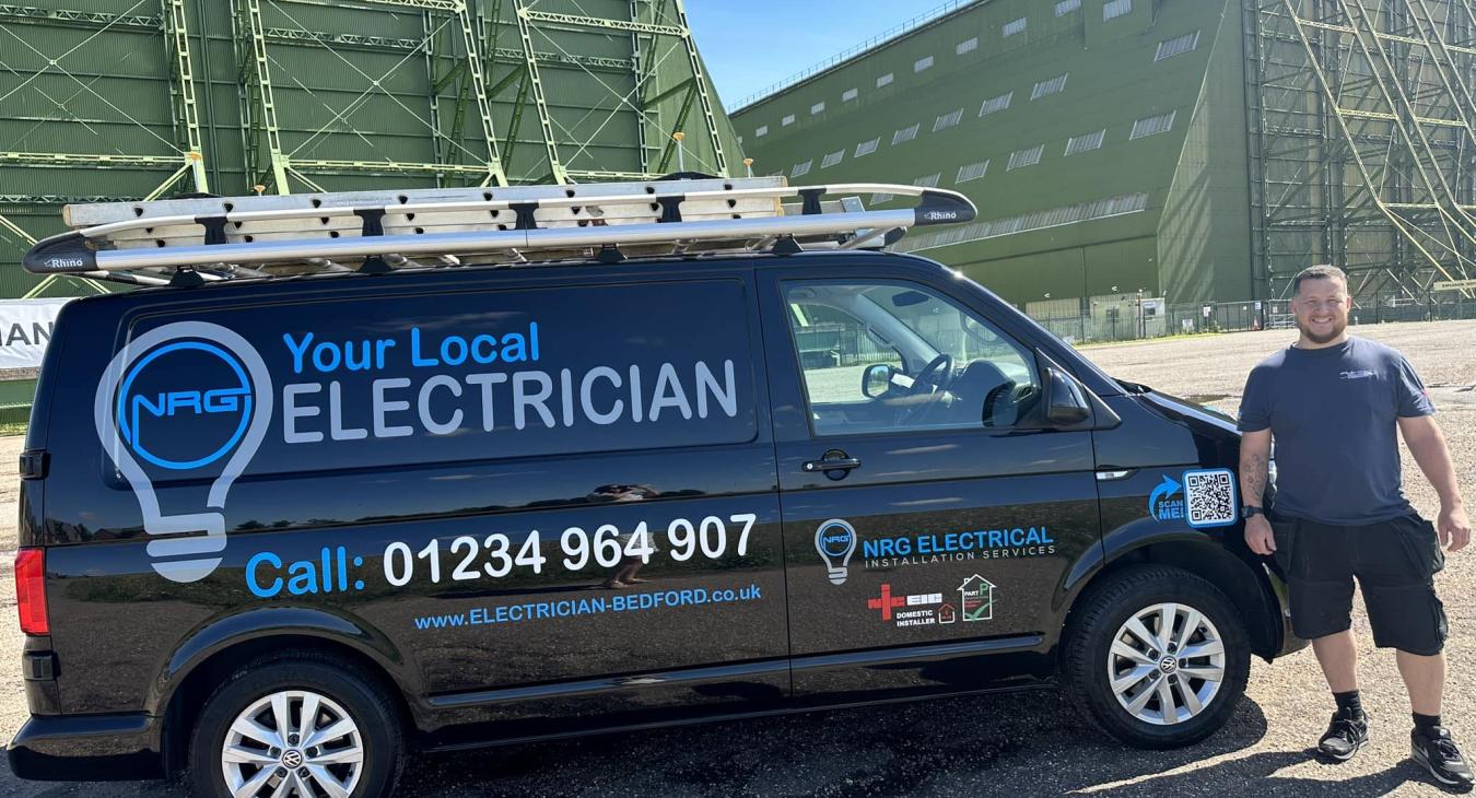 Electrician standing in front of his work van in Bedford